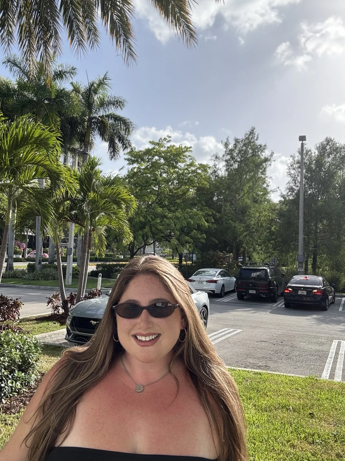 Taylor smiling outdoors beneath palm trees